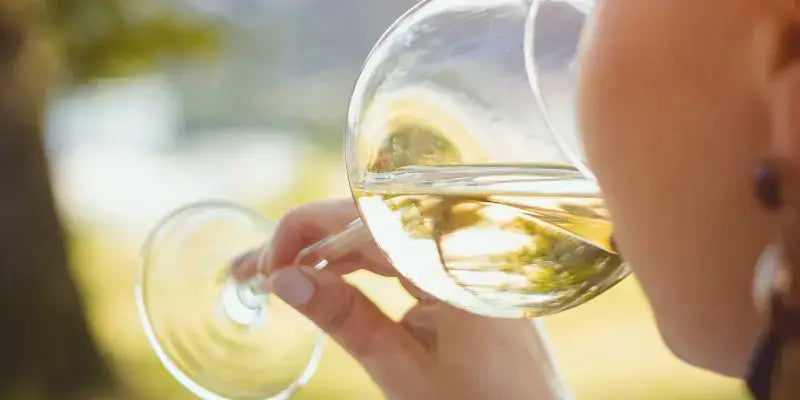 Liebliche Weine: Porträt einer Person, die ein Glas süßen Wein in der Natur genießt.