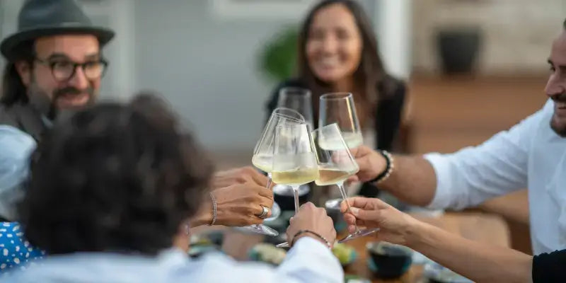 Wein-Tasting bei TIME 2 TASTE: Kollegen stoßen mit Weingläsern an, genussvolle Atmosphäre.
