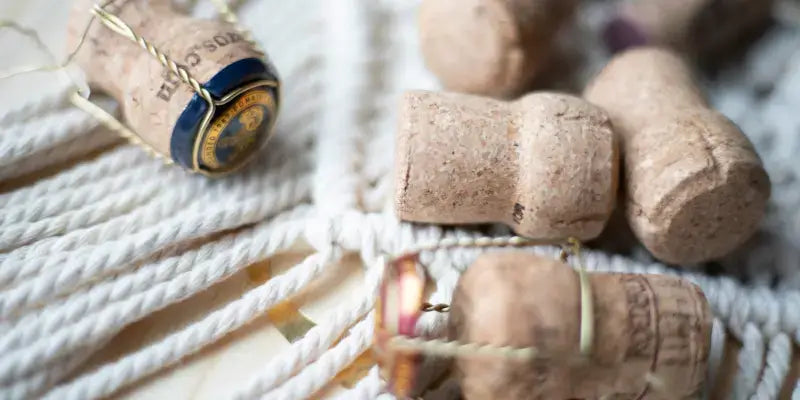 Schaumwein mit Jahrgang: Korken von Schaumweinflaschen auf einem geflochtenen Untergrund.