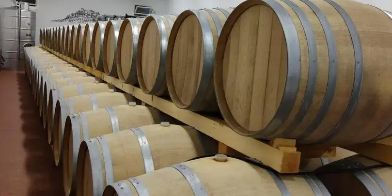 Kraftvoller Merlot von Torre Rosazza: Holzfässer im Weinkeller, repräsentieren die Reifung und Qualität des Weins.