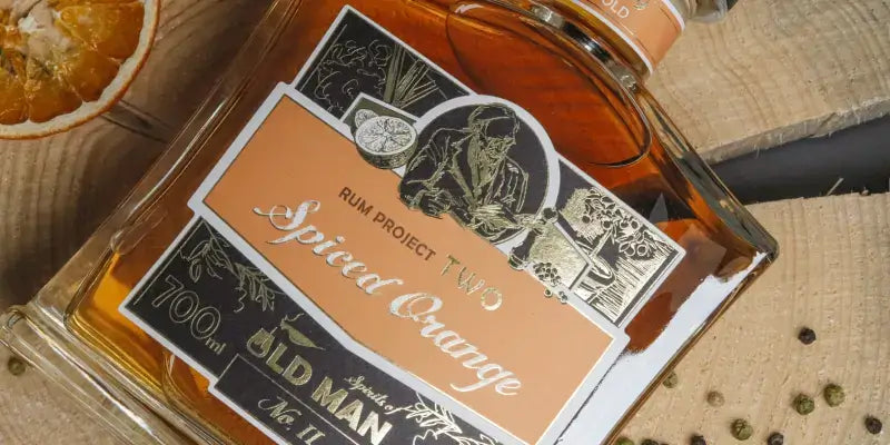 Old Man Spirits Flasche Spiced Orange auf Holzuntergrund mit Orangenscheibe, Rum-Genuss aus dem hohen Norden.