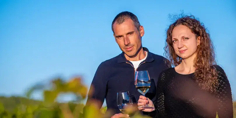 Entdecke den edlen Cava: Zwei Personen genießen Cava in einem Weinberg bei sonnigem Wetter.