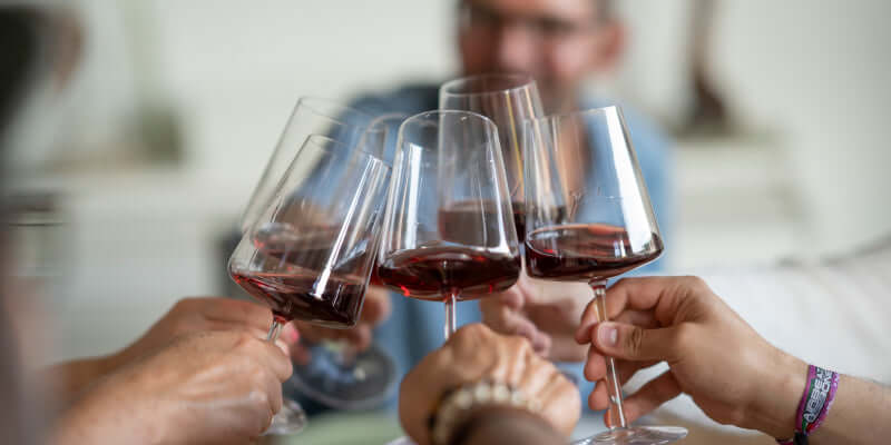 Rotwein genießend: Anstoßen mit Glas in geselliger Runde, schmeckende Vielfalt erleben.