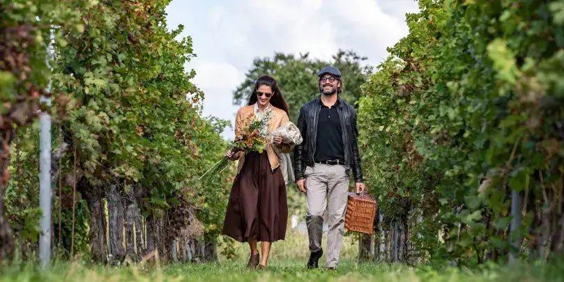 Cecilia Beretta Prosecco Extra Dry: Paar bei einer Ernte in einem Weinberg, umgeben von Traubenreben.
