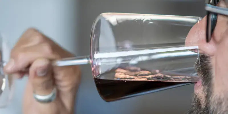Wein auf dem Höhepunkt: Mann verkostet Rotwein aus einem Glas und beurteilt die Trinkreife.