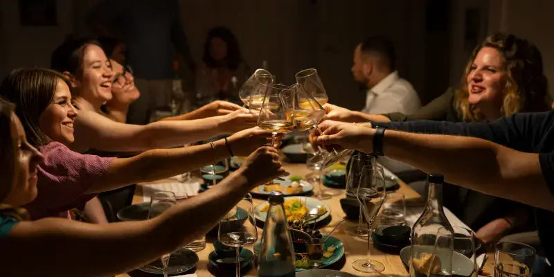 Wein-Tasting während einer Betriebsfeier mit fröhlichen Gästen, die Gläser anstoßen und genießen.
