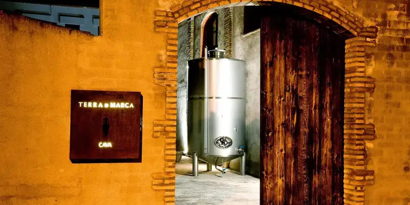 Terra de Marca: Eingangsbereich zum Weingut mit silbernem Tank und Holzportal in Katalonien.