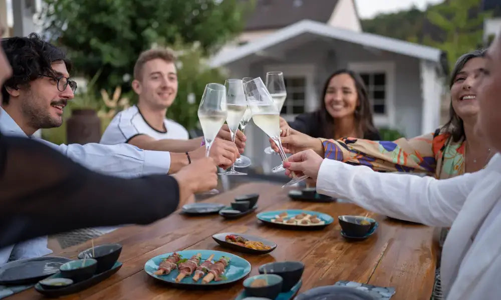 Dein Sekt Tasting in Karlsruhe: Gruppe, die mit Sekt und Fingerfood an einem Tisch anstößt.