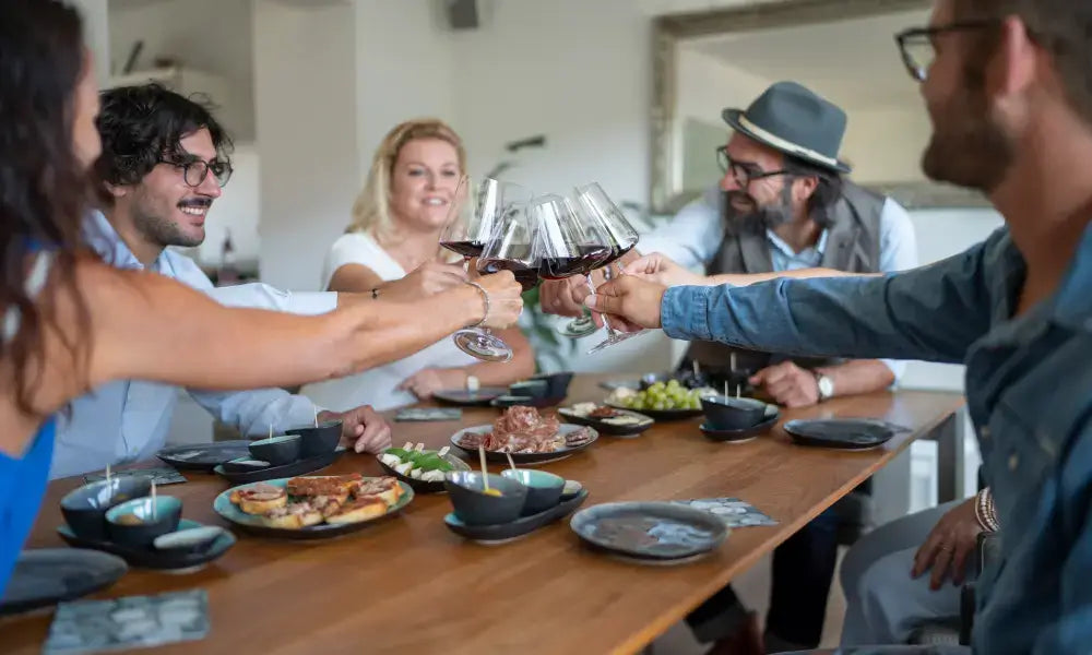 Dein Wein Tasting in Lahr: Feiernde Freunde bei Weinprobe mit Antipasti und tapas am Tisch, fröhliche Atmosphäre.