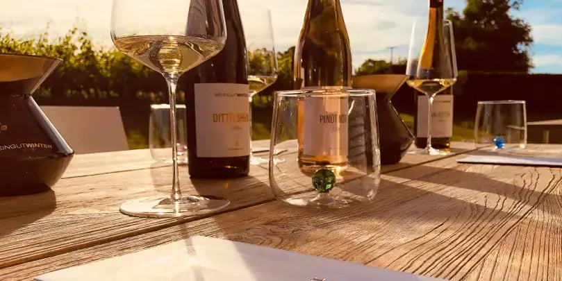 Dittelsheim Riesling - Erste Lage VDP auf einem Tisch mit Weingläsern in Weinberg-Umgebung bei Sonnenlicht.