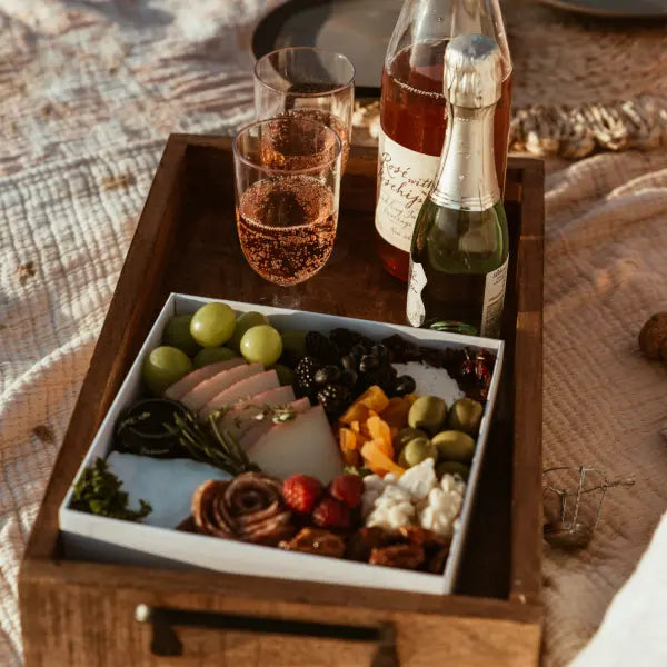 Genießen Sie ein vielseitiges Käse- und Obstbrett mit Sekt, perfekt für festliche Anlässe im Freien.