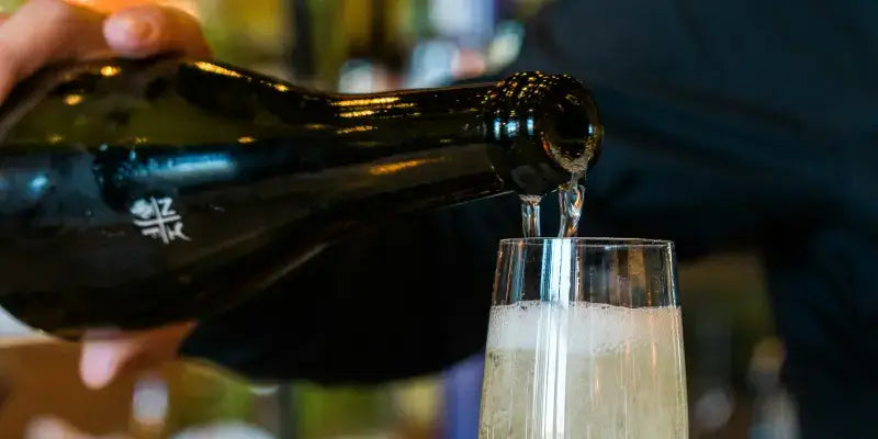 Champagner wird aus einer Flasche in ein Glas eingeschenkt, um den prickelnden Genuss zu erleben.