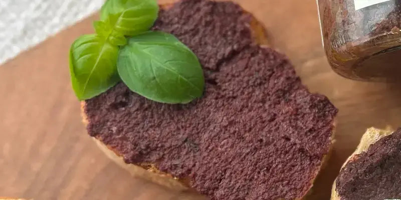 Olivencreme auf geröstetem Baguette mit frischem Basilikum, mediterraner Genuss für Feinschmecker.