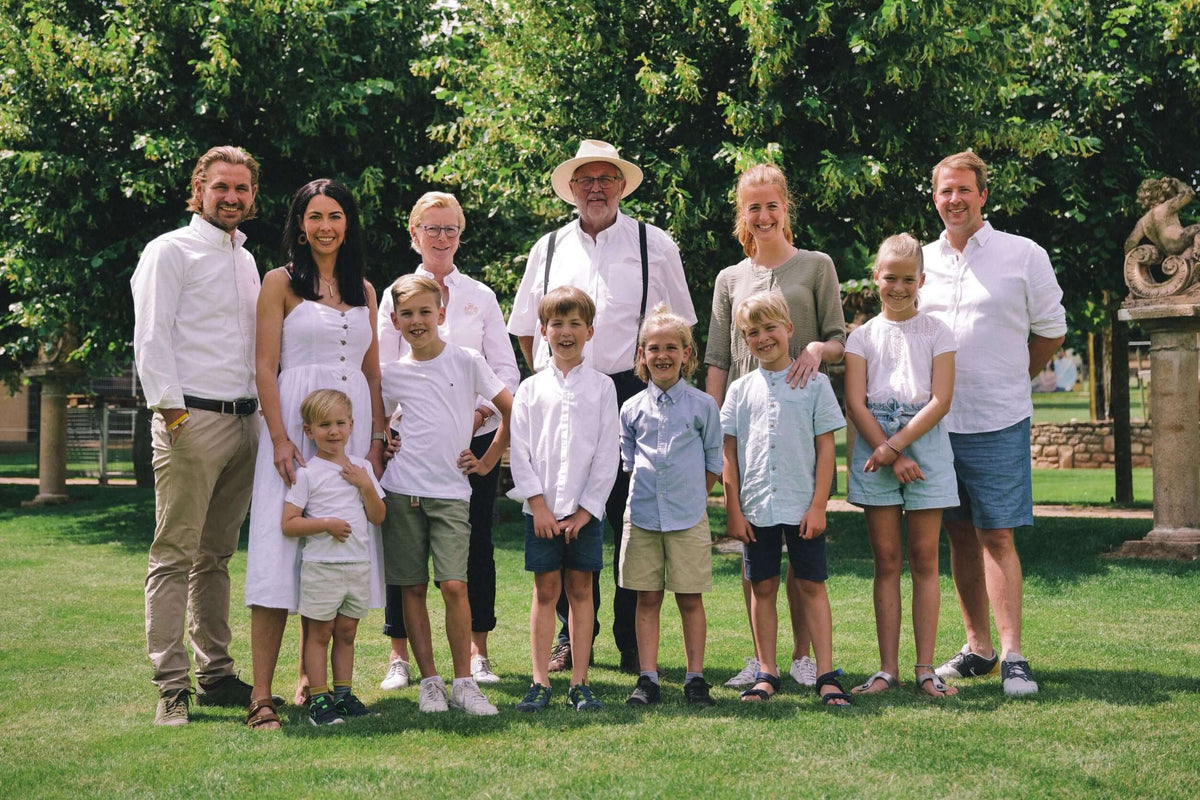 Weingut Lorenz & Söhne: Familie und Kinder am Weinberg in elegantem Outfit auf grünem Rasen.