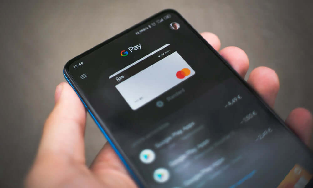 In der Hand ein Smartphone mit google pay auf dem Bildschirm