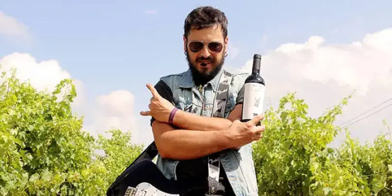 Wines N' Roses Highway to Hell – Mann mit Weinflasche und Gitarre in Weinberg, Rock'n'Roll Spirit im Weinglas.