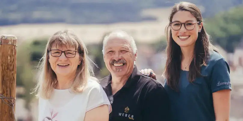 Weingut Udo Weber – Familie Weber im Weinberg, strahlend unter blauem Himmel, mit Weinfeldern im Hintergrund.