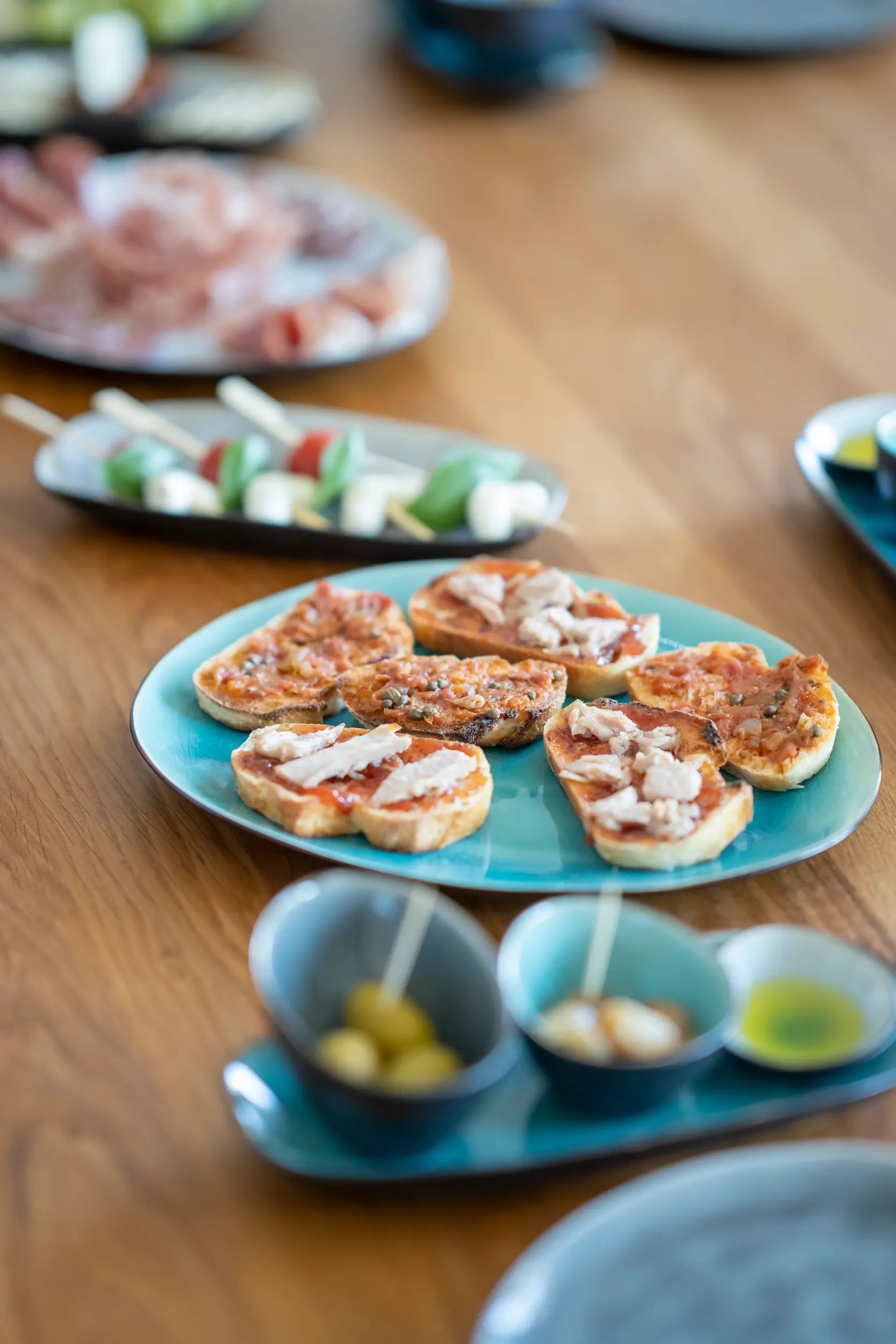 Unterschiedliche Tapas auf bunten Tellern stehen auf einem Tisch für das Tasting