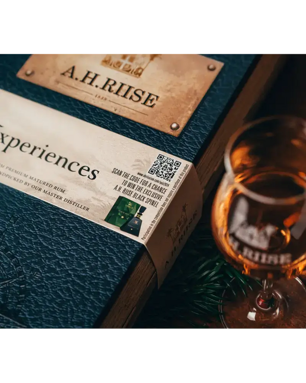 A.H. Riise Rum Adventskalender 2024 mit QR-Code und Verkostungsglas in stilvoller Präsentation.