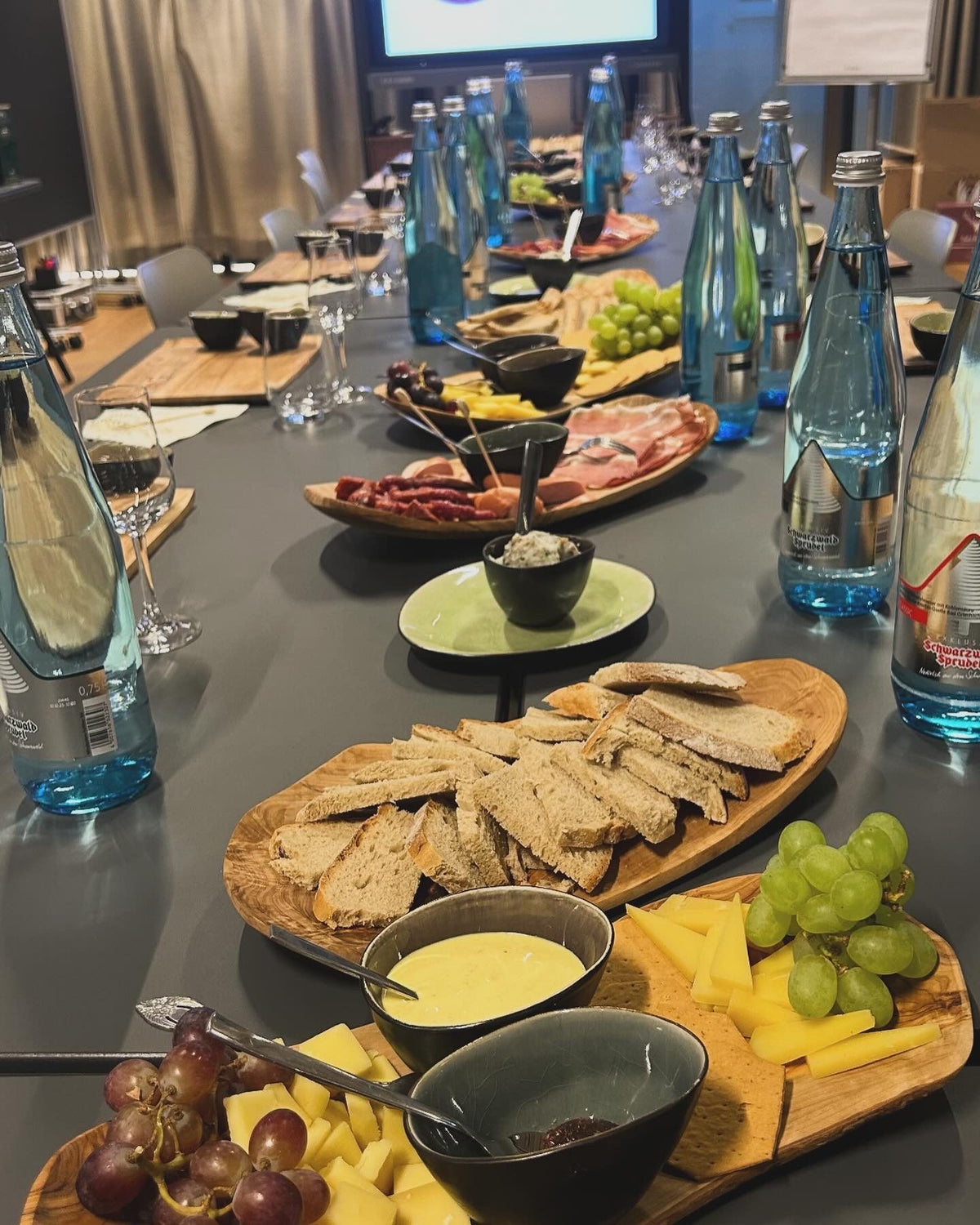 Gedeckter Tisch für ein Firmen-Tasting mit Käse, Schinken, Brot und Wasser