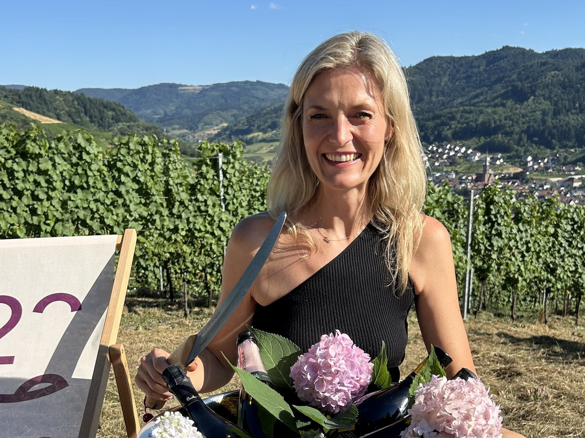 Frau mit Säbel und Champagnerkühler zur Sabrage in den Weinbergen