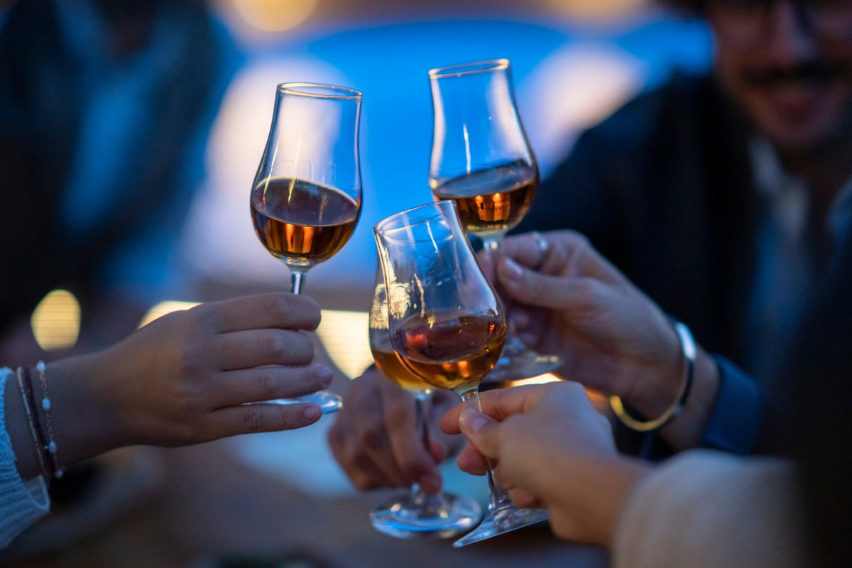 Anstoßen mit Rum und Whisky in Tasting-Gläsern am Abend