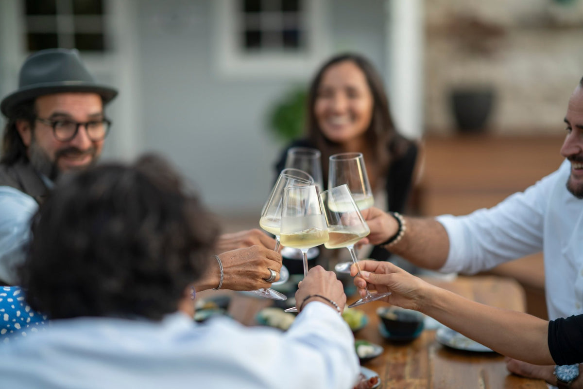 Gäste stoßen im Freien mit Weißwein an