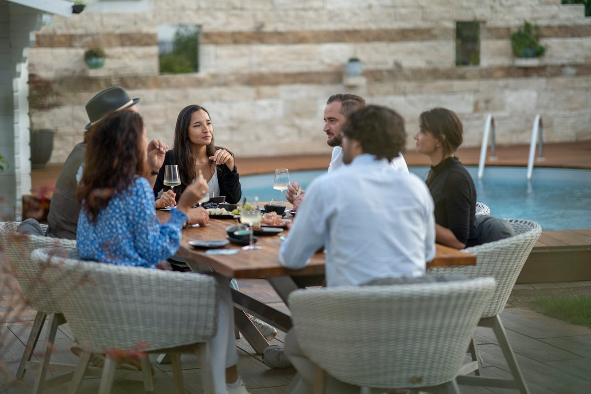 Runde mit Weißwein und Fingerfood am Tisch im Garten neben dem Pool