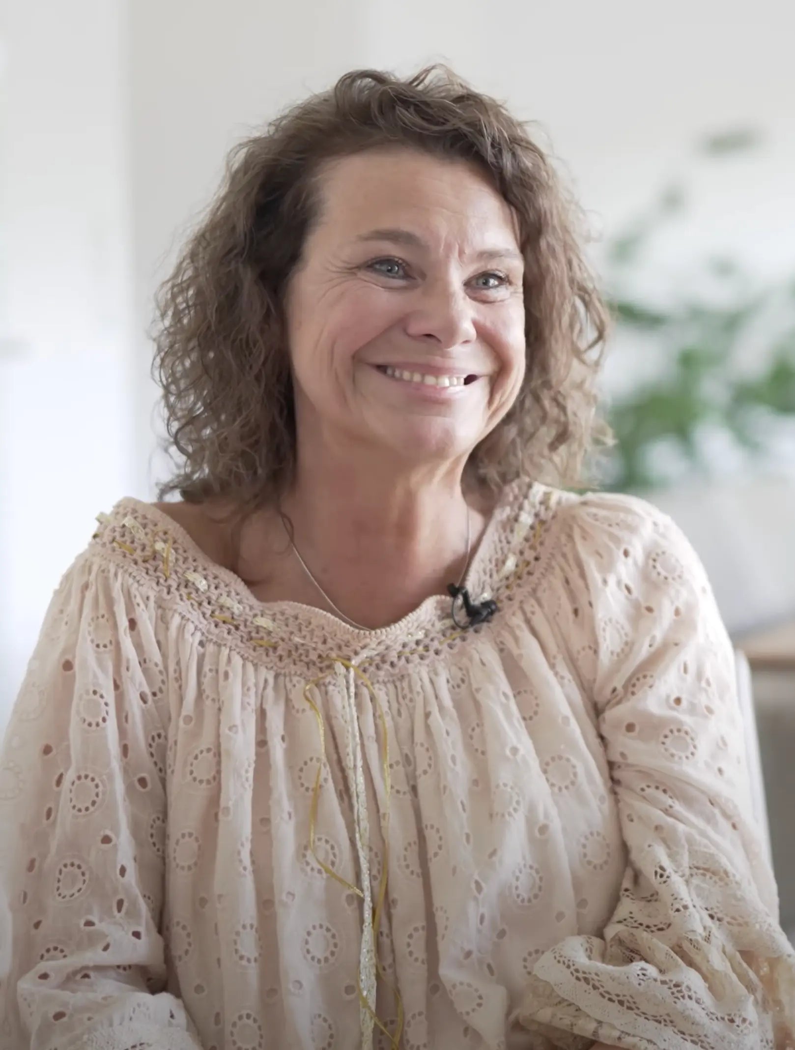 Ihr Name ist Nadja und sie trägt trägt eine beige Bluse und strahl vor Freude