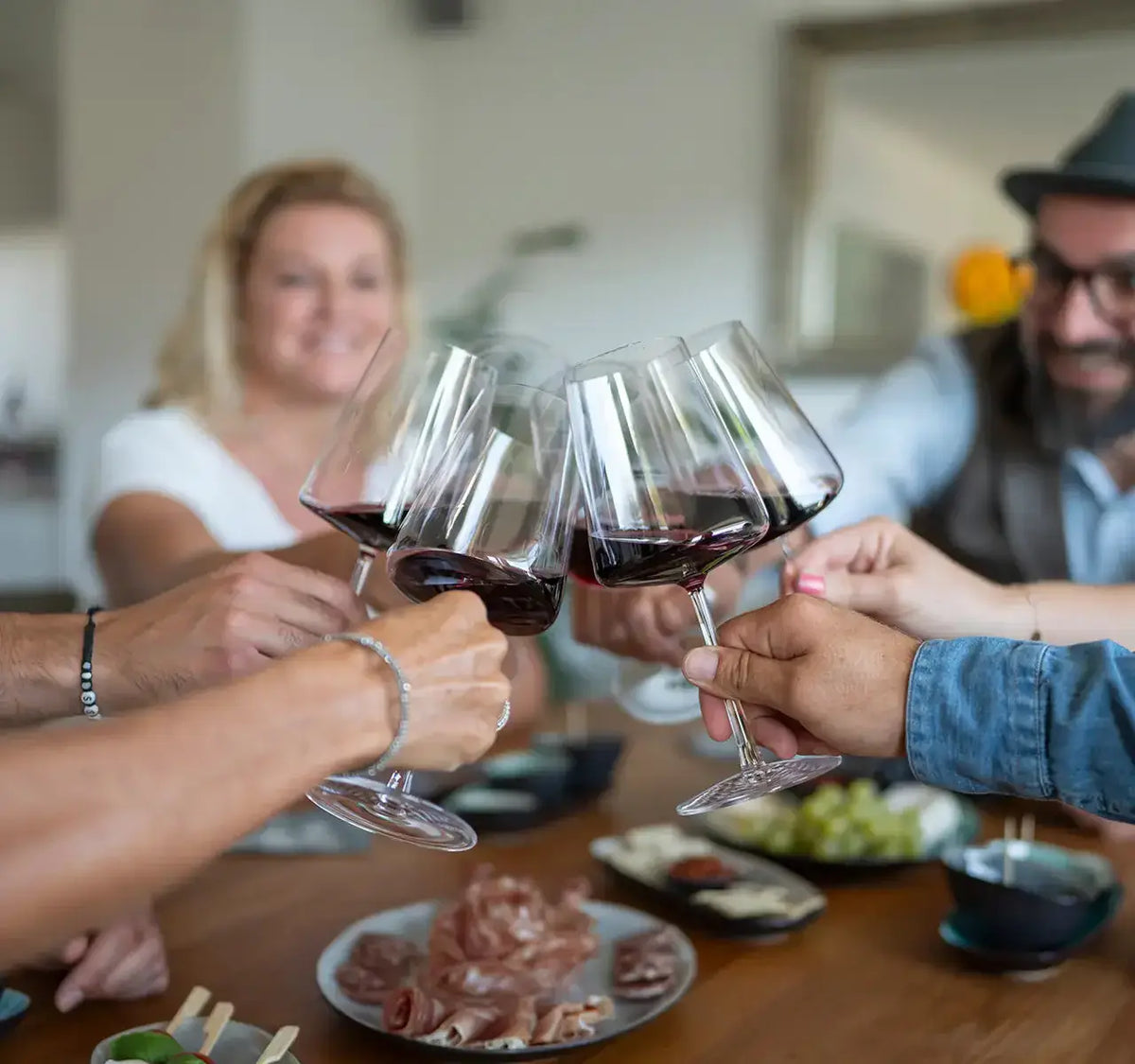 Wein Tasting für Fortgeschrittene mit spanischen Tapas, fröhliche Gruppe beim Anstoßen mit Rotweingläsern.