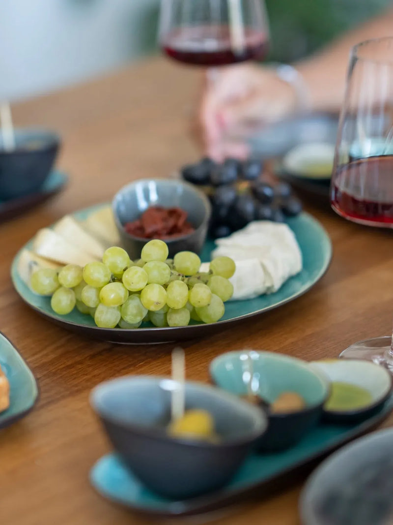 Tapas, Käse, Trauben und ein Glas Rotwein auf dem Tisch