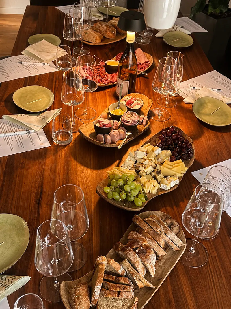 Gedeckter Tisch mit Weingläsern, Käse, Wurst und Brot für eine Weinprobe