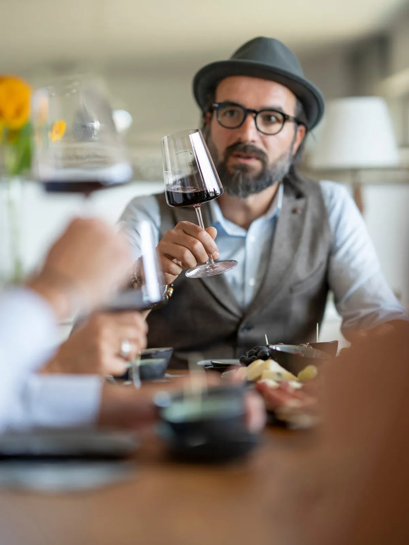 Ein Glas Rotwein wird bei der Weinprobe betrachtet