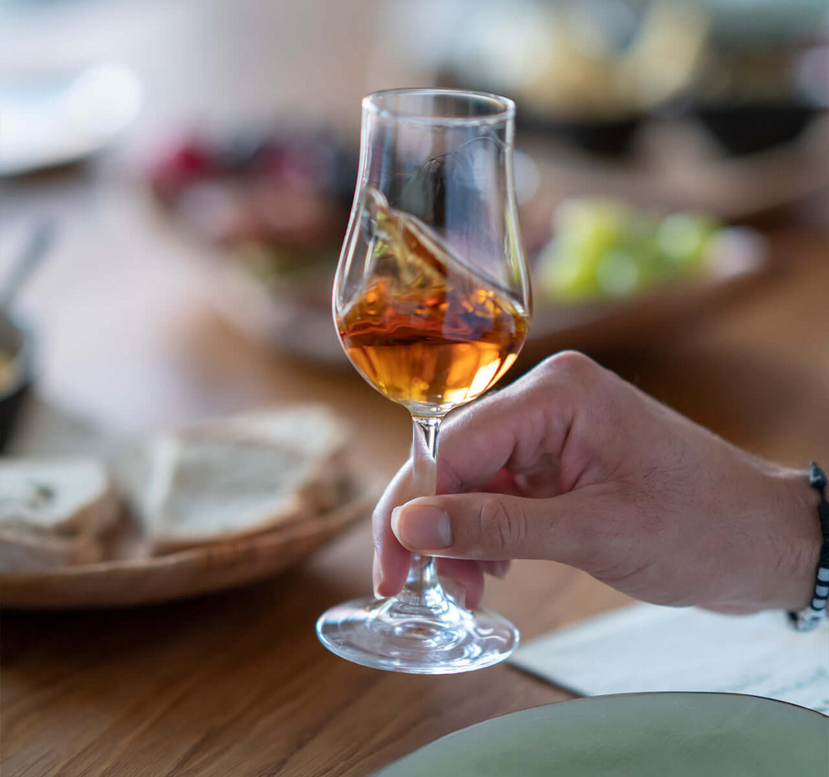 Whisky Tasting für Kenner mit edlem Glas und begleitenden Köstlichkeiten auf einem gedeckten Tisch.